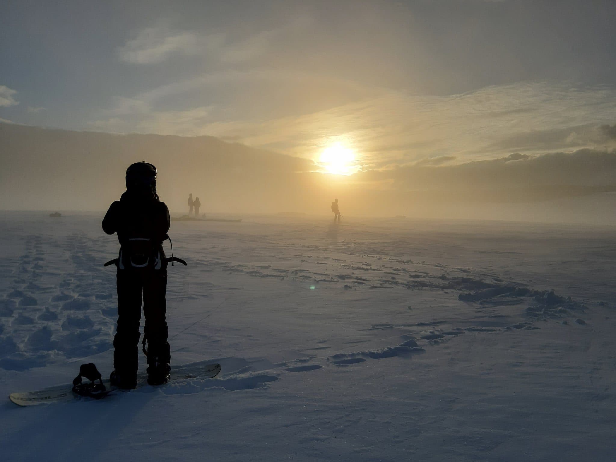 Snowkiteři při západu slunce na pláni u Komárky